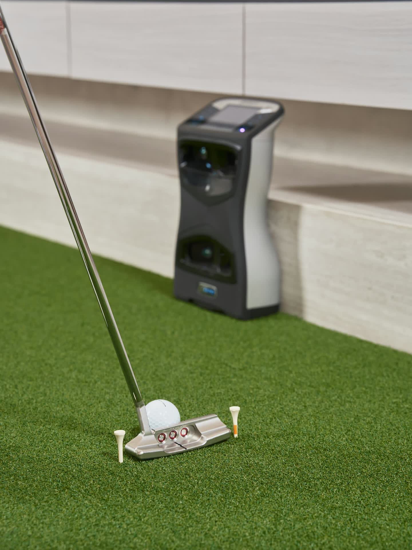 Launch monitor, putter and ball on pristine turf